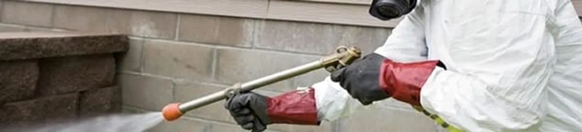 Pest control technician applying exterior insect treatment along a home foundation in Scottsdale, AZ
